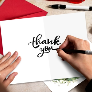 Primer plano de escritura en tarjeta de agradecimiento blanca con un sobre rojo elegante