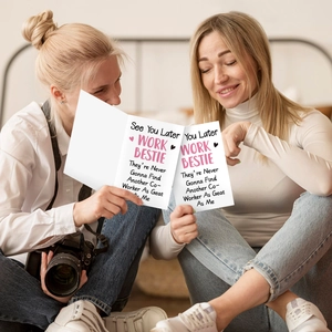 Two colleagues sharing a folded farewell card in a warm indoor lifestyle setting