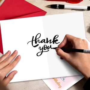 Macro shot of minimalist white thank you card with cursive text and red envelope