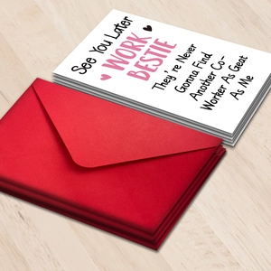 Macro shot of Work Bestie farewell cards and red envelopes on light wood background
