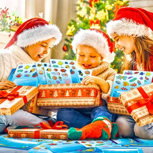 Drei Kinder mit Weihnachtsmützen öffnen ein Sticker-Set mit Unterwasserwelt-Motiven