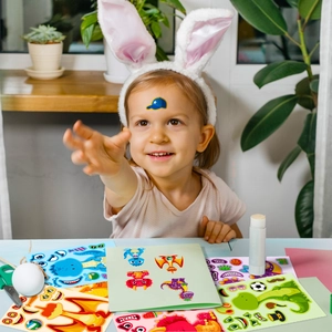Girl playing with colorful cartoon dinosaur stickers for creative DIY make-a-face activity