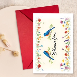 Floral thank you card with blue birds and a vibrant red envelope on rustic linen fabric