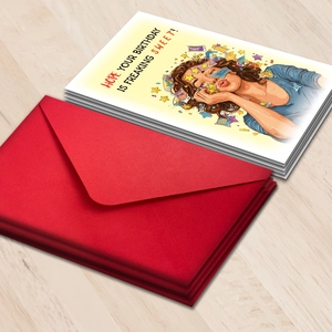 Macro shot of large humorous birthday cards with red envelopes on wood background