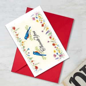 Macro view of floral thank you card with watercolor bluebirds and a premium red envelope