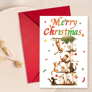 Nahaufnahme der Weihnachtskarte mit Katzenmotiv und rotem Umschlag auf Teller
