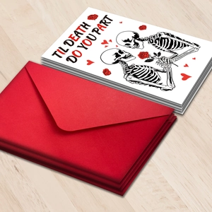 Set de tarjetas de San Valentín con pareja de calaveras y sobres rojos sobre mesa de madera