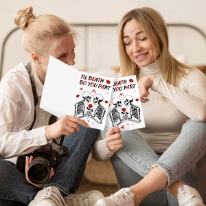 Mujeres sostienen tarjeta de San Valentín con calaveras y texto Till Death Do Us Part