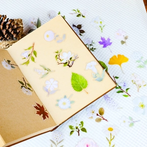 Detailed close-up of white flowers and green leaves PET stickers on a leather notebook