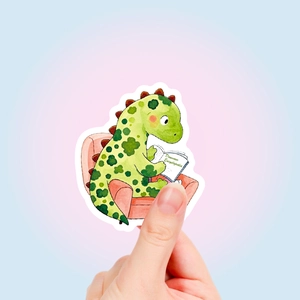 Detailansicht eines handgehaltenen Dinosaurier-Aufklebers beim Lesen für Scrapbooking