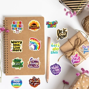 Detailed view of inspirational quote stickers on a white desk with craft stationery