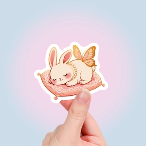 Close-up of a cute sleeping bunny sticker with wings and pearls for DIY journaling