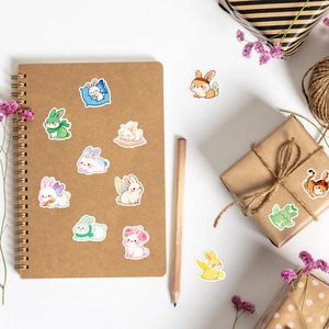 Flat lay of cute cartoon rabbit stickers on a kraft notebook and gift box with dry flowers