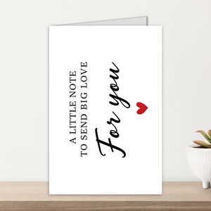 Detail of white greeting card with big love text on a wooden surface with succulent