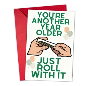 Close-up of birthday card with 'Just Roll With It' text and red envelope set