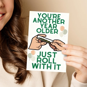 Close-up of birthday card with humor roll illustration and colorful party balloons