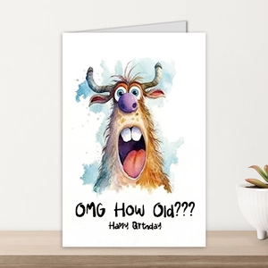 Carte d'anniversaire drôle avec vache et texte OMG How Old sur un bureau en bois