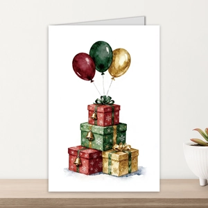 Vertical folded greeting card featuring watercolor gift boxes and balloons on a wood desk