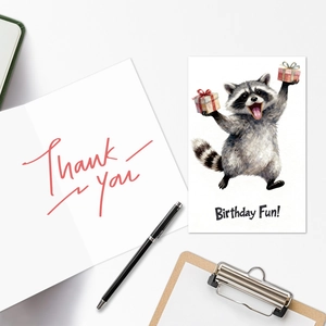 Detail of watercolor raccoon birthday card and thank you card set on a white desk