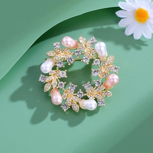 Elegant gold pearl wreath brooch with sparkling rhinestones for women on green pedestal
