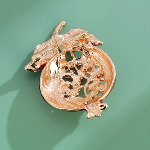 Vue arrière d'une broche grenade minimaliste plaquée or avec épingle sur fond vert d'eau