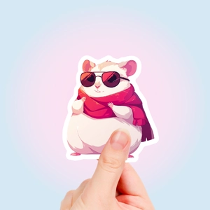 Detail view of a cute hamster sticker with sunglasses and a red scarf held by fingers