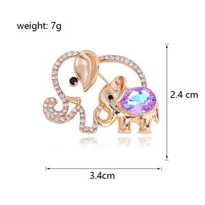 Golden hollow elephant brooch with purple crystal and white rhinestones on white background