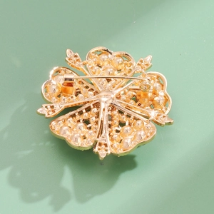 Back view of a gold flower brooch with detailed hammer texture and secure pin clasp