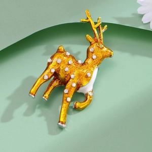 Broche renne dorée avec émail blanc et strass étincelants sur un fond vert doux
