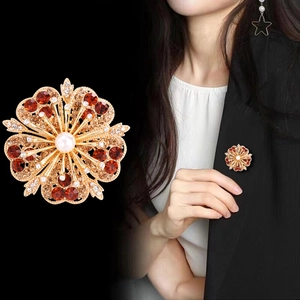 Elegant floral brooch with red rhinestones and a central pearl on a black blazer