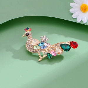 Élégante broche paon avec cristaux de couleur en forme de goutte et finition dorée sur fond vert