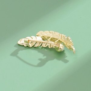 Golden feather brooch with elegant white pearl and detailed metal texture on the back side
