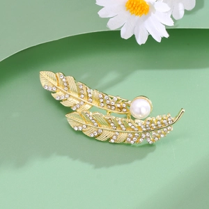 Elegant gold feather brooch with sparkling crystals and a large white pearl center