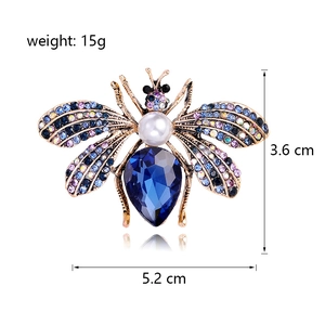Vintage gold bee brooch with blue crystal, pearl and colorful rhinestones on white background