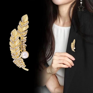 Elegante spilla a piuma dorata con cristalli bianchi e perla indossata da modella
