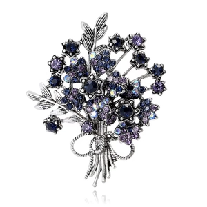 Broche bouquet élégante avec cristaux violets et bleus sur surface réfléchissante