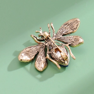 Back view of a vintage gold bee brooch with blue gemstone and secure safety pin clasp