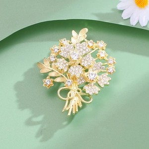 Élégante broche bouquet de fleurs dorée avec cristaux étincelants et un nœud délicat