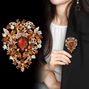 Broche vintage dorado con piedras ámbar y cristales, visto en modelo y en primer plano