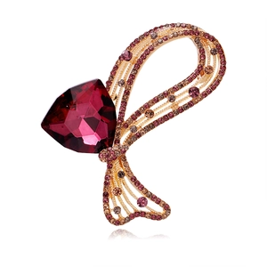Détail d'une broche nœud de luxe avec pierre triangulaire rouge et strass multicolores