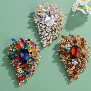 Elegant gold-tone floral crystal brooch set with vibrant rhinestones on a green background