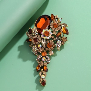 Vintage crystal flower brooch with amber stones and drop pendants on a green background