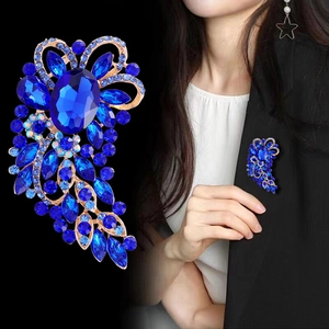 Vintage style gold brooch with deep blue crystals and oval center stone on a blazer