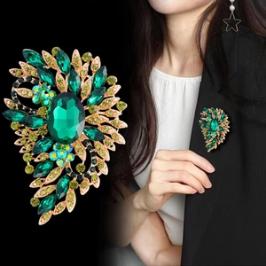 Elegant emerald green glass brooch with glittering rhinestones on gold-tone metal base