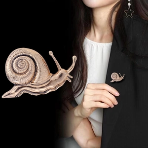 Détail macro d'une broche escargot en bronze vintage sur le revers d'un tailleur noir