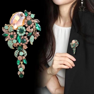 Vintage oversized floral brooch with green crystals and champagne rhinestones on black background