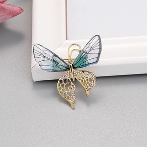 Détail d'une broche papillon avec ailes bleu-vert et cristaux brillants sur métal doré