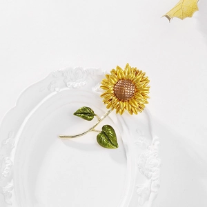 Close-up of vibrant sunflower brooch featuring layered yellow petals and green leaves