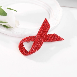 Macro shot of red ribbon brooch featuring dense red rhinestones on a white ceramic plate