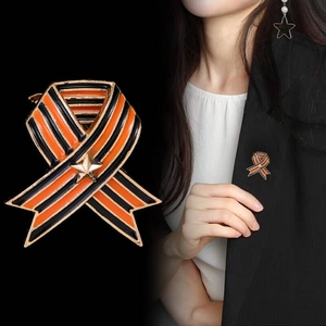 Macro detail of alloy brooch with orange and black stripes and gold star on clothing